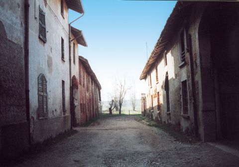 Il borgo: strada acciottolata, costeggiata da due file di case  depoca, che si apre sui campi.