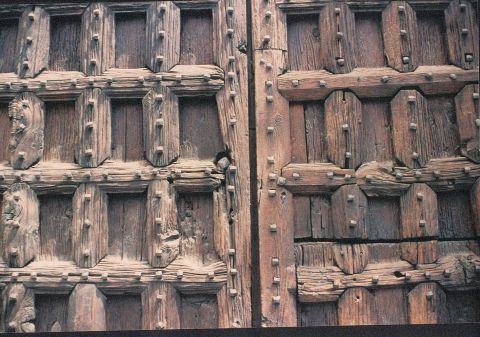 Particolare della facciata dellAbbazia: antico portone ligneo con grossi chiodi di  ferro fatti a mano.